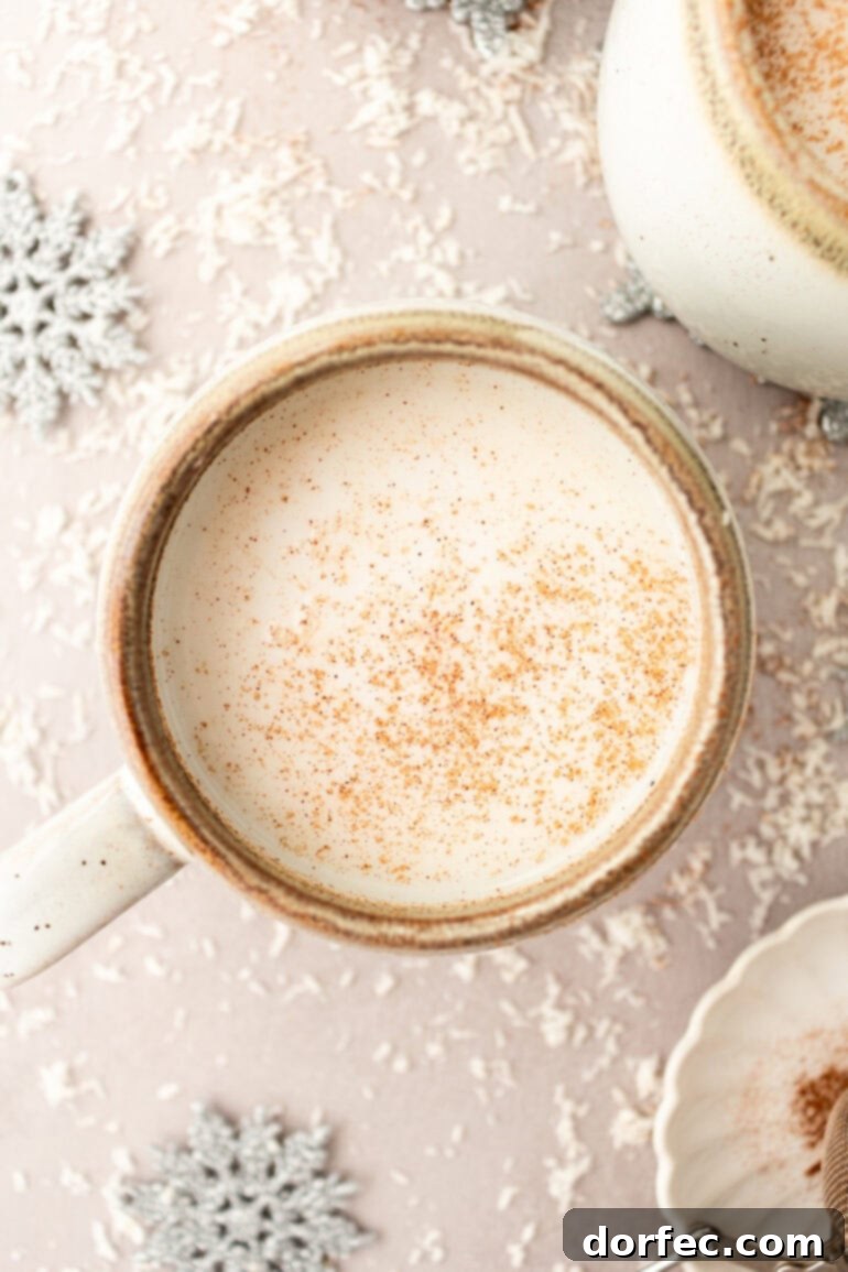 A photo taken over the top of a vanilla steamer in a mug topped with cinnamon, highlighting its inviting warmth and comforting aroma.