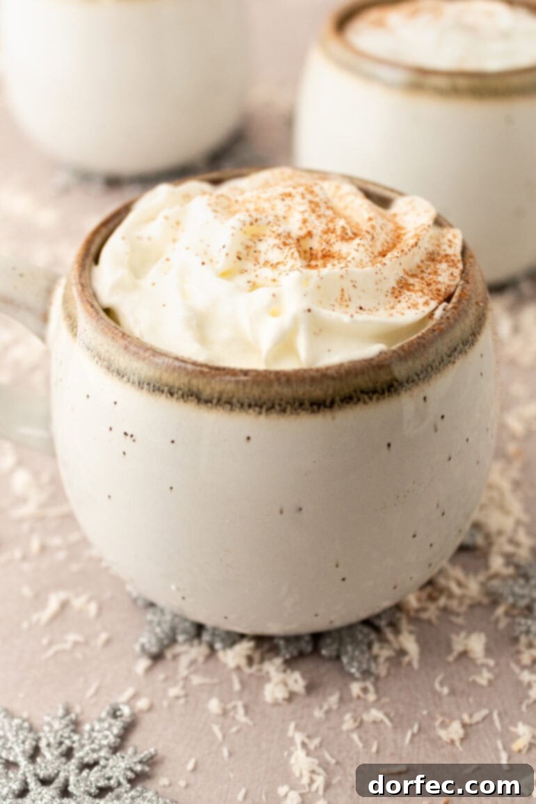A photo of a mug of warm vanilla milk, elegantly topped with whipped cream and sprinkled with cinnamon, suggesting a delightful treat.