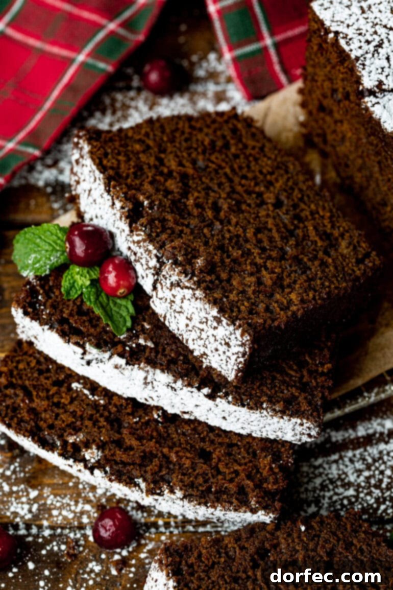 Classic Gingerbread Loaf 2 A photo of several deliciously moist gingerbread loaf slices, artfully arranged and garnished with whole cranberries and fresh greenery.