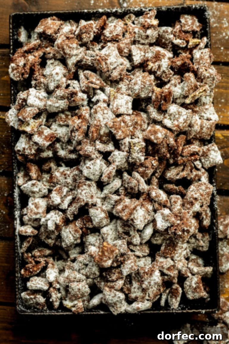 a baking sheet full of dark chocolate muddy buddies mix coated in powdered sugar