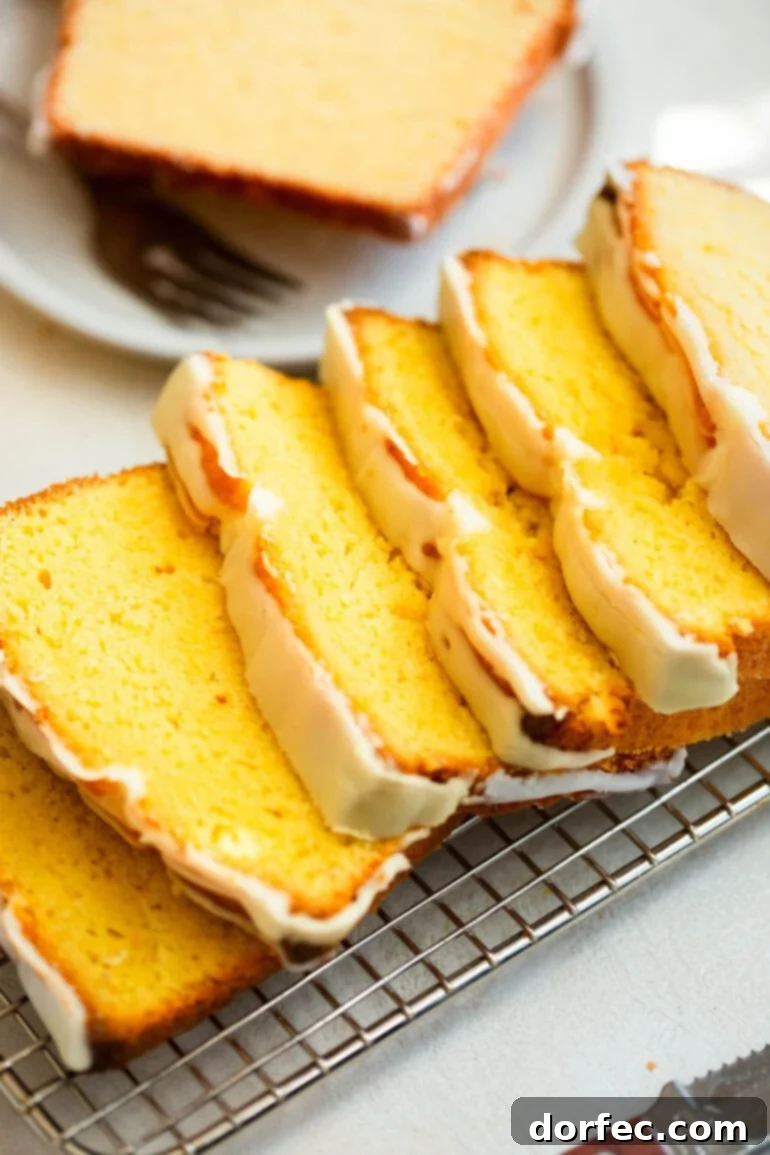 Zesty Lemon Glazed Loaf 3 A beautifully baked loaf of lemon pound cake, meticulously sliced into thin, even pieces, resting on a wire cooling rack.