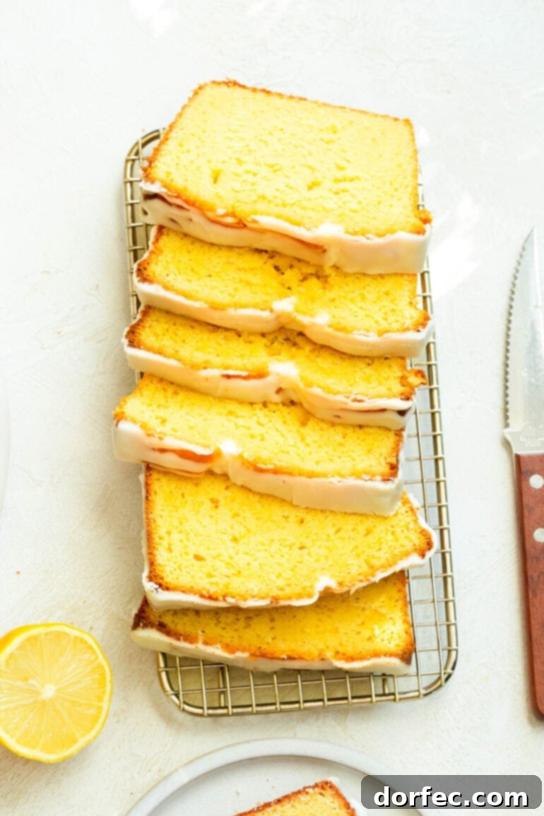Zesty Lemon Glazed Loaf 6 A golden-brown lemon pound cake, expertly sliced into thin, inviting pieces, arranged on a wire cooling rack with a kitchen knife beside it.