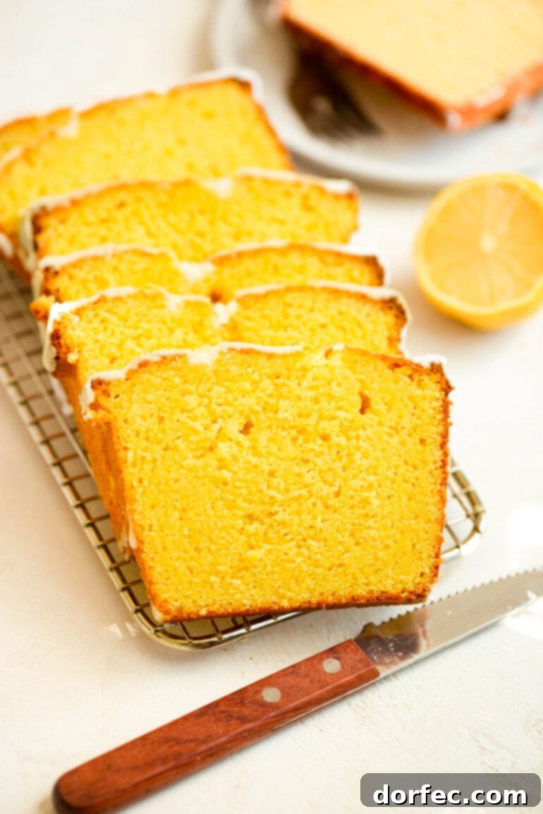 Zesty Lemon Glazed Loaf 8 Beautifully sliced lemon loaf cake, with thin pieces gently layered on a wire cooling rack, highlighting its moist, golden crumb.