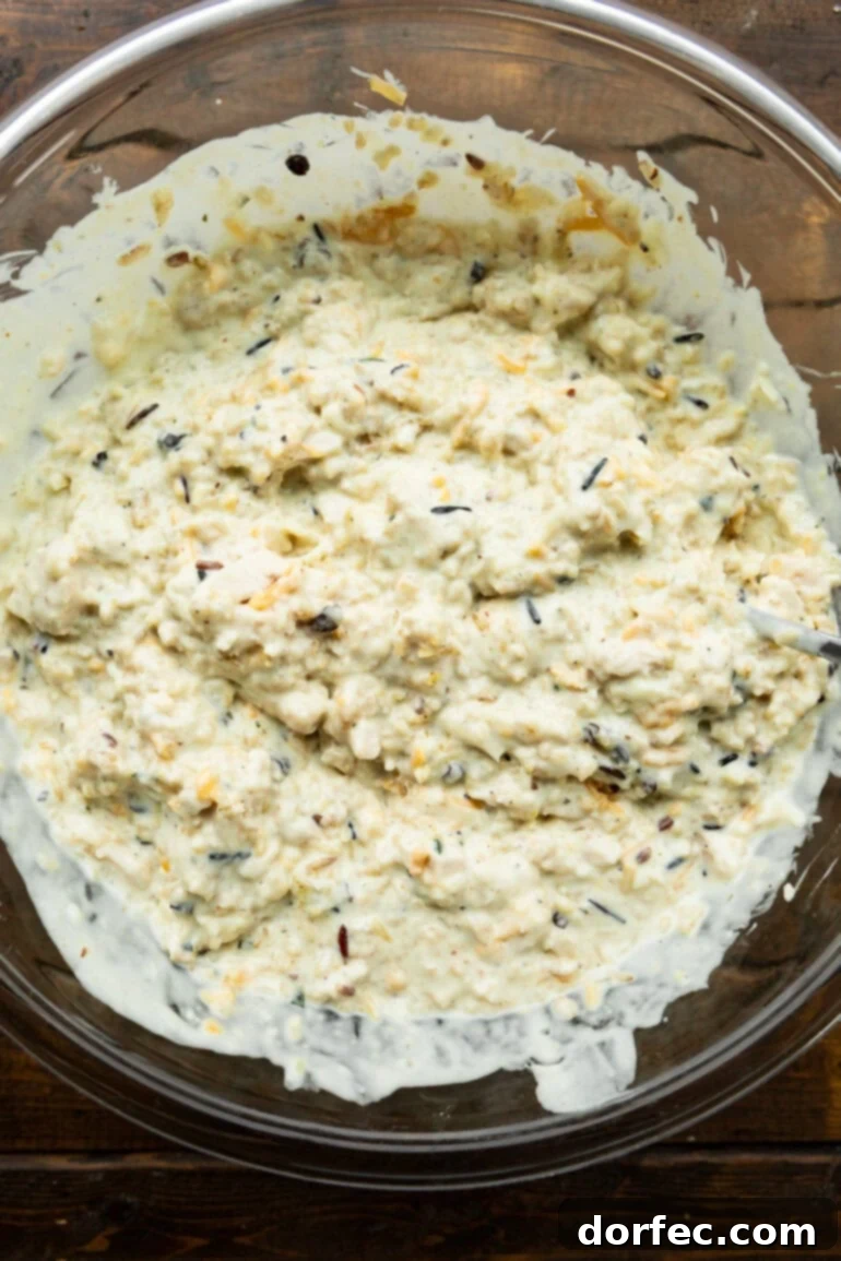 Super Creamy Cheesy Chicken and Rice Casserole 5 A large mixing bowl filled with the combined ingredients for cheesy chicken and rice casserole, ready to be transferred to a baking dish for the oven.