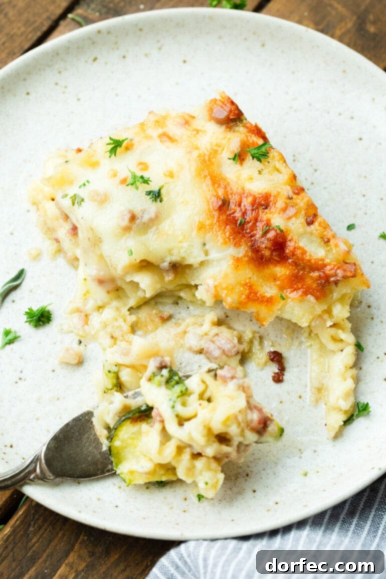 A photo of a serving of pancetta vegetable lasagna being cut into with a fork, showing the distinct layers and inviting texture.