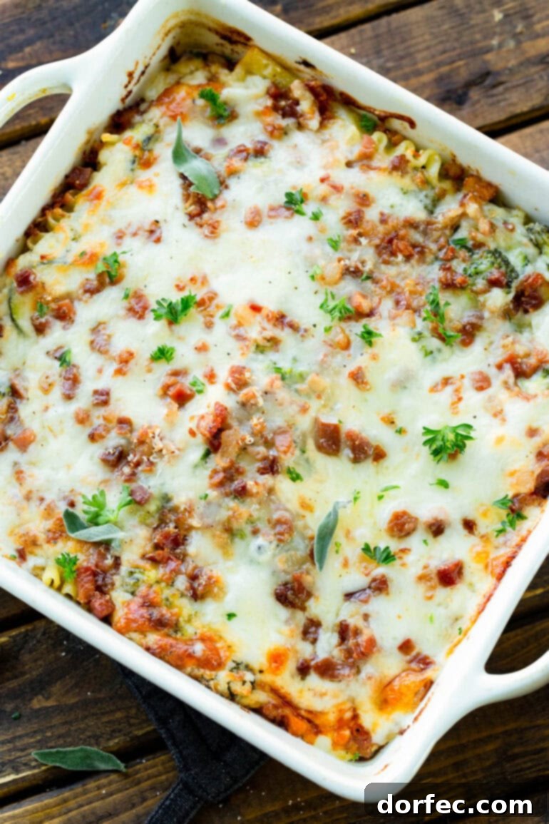 A photo of an 8x8 white casserole dish full of golden baked pancetta vegetable lasagna with white sauce, fresh out of the oven.