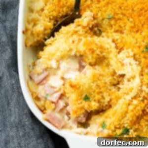 A photo of a Chicken Cordon Bleu Casserole with a serving being removed, showcasing its delicious layers and golden topping.