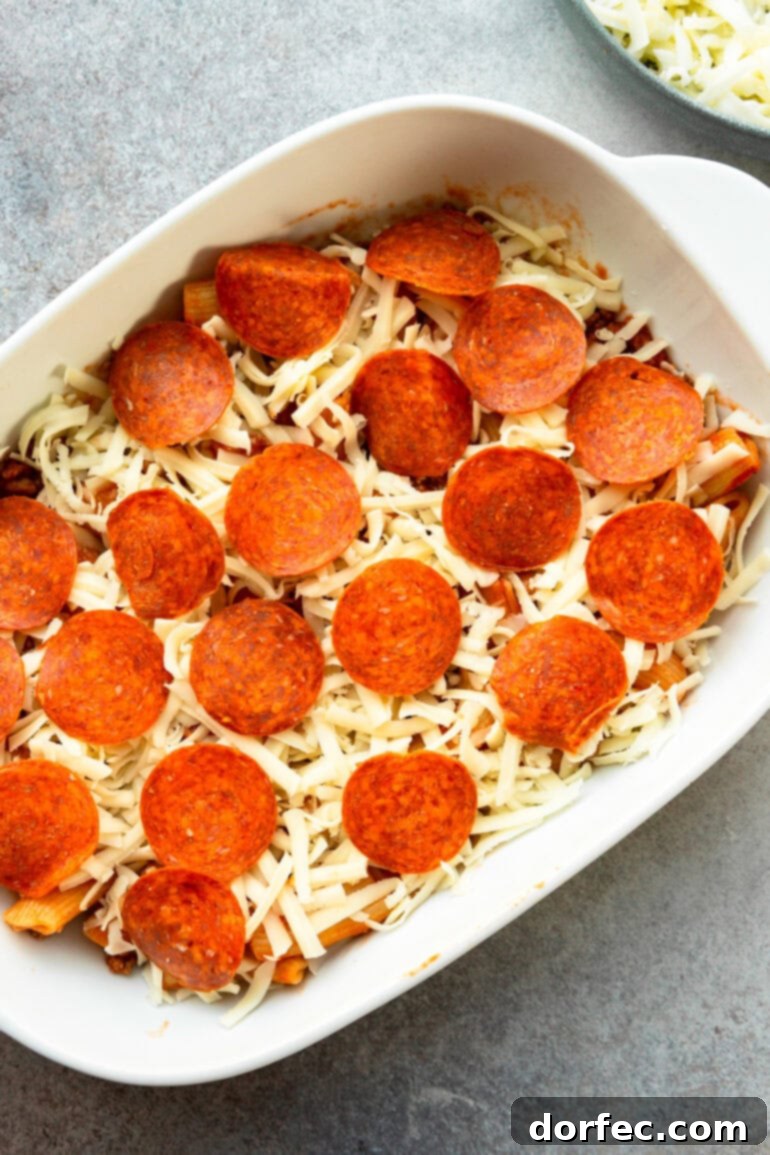 a photo of a pizza casserole ready to go in the oven will grated mozzerella on top and pepperonis