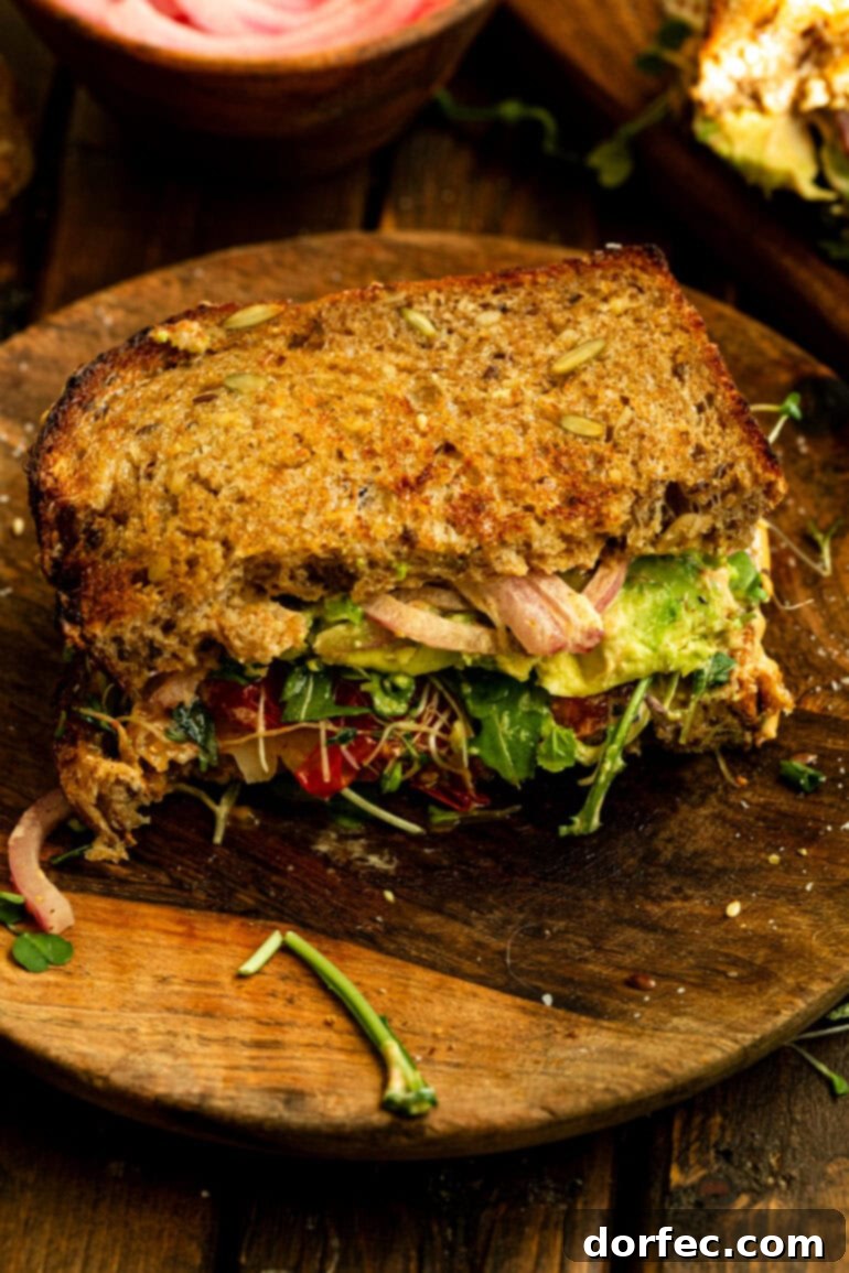 A perfectly toasted multigrain avocado sandwich, cut in half and elegantly presented on a wooden plate, ready to be devoured as a healthy and satisfying meal.