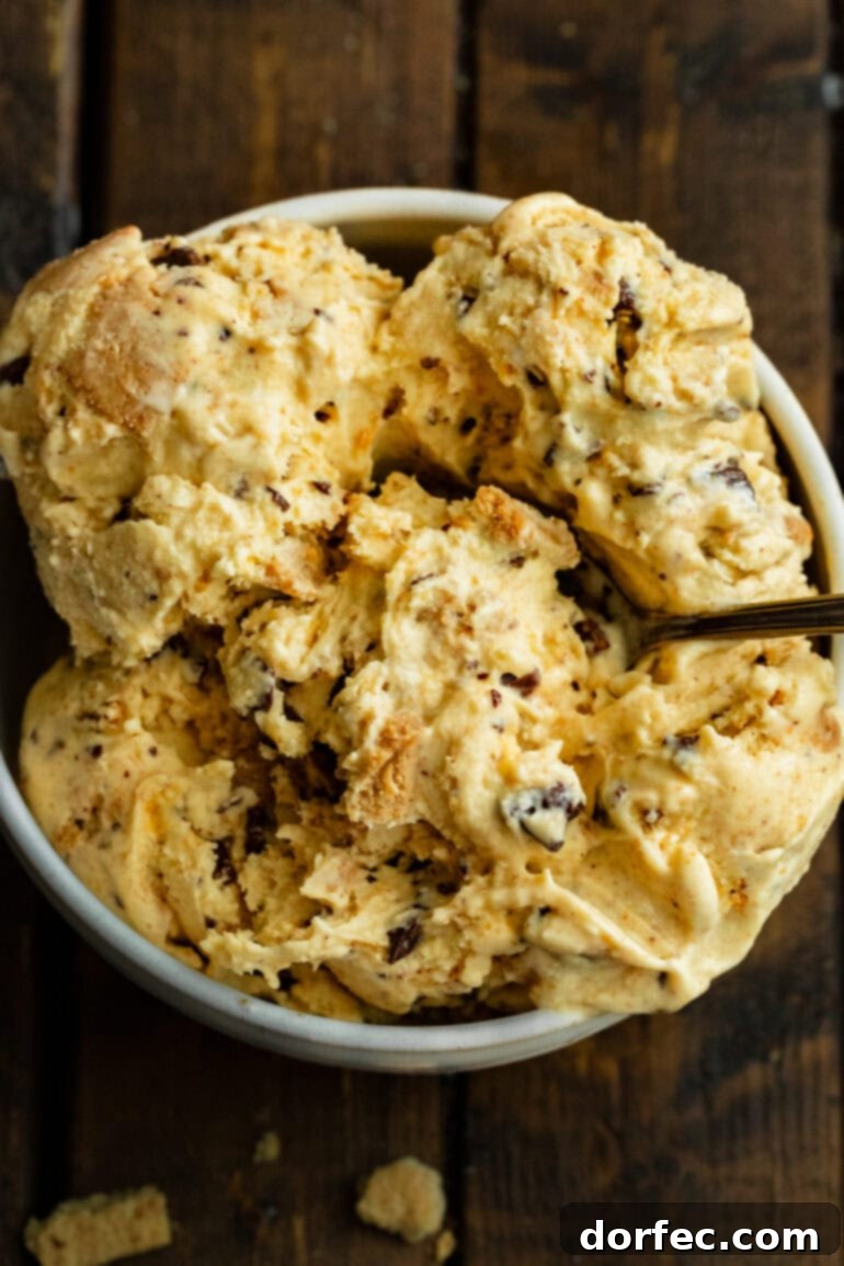A close-up of a large bowl showcasing multiple scoops of graham cracker ice cream, generously laden with chocolate-covered honeycomb pieces, inviting indulgence.