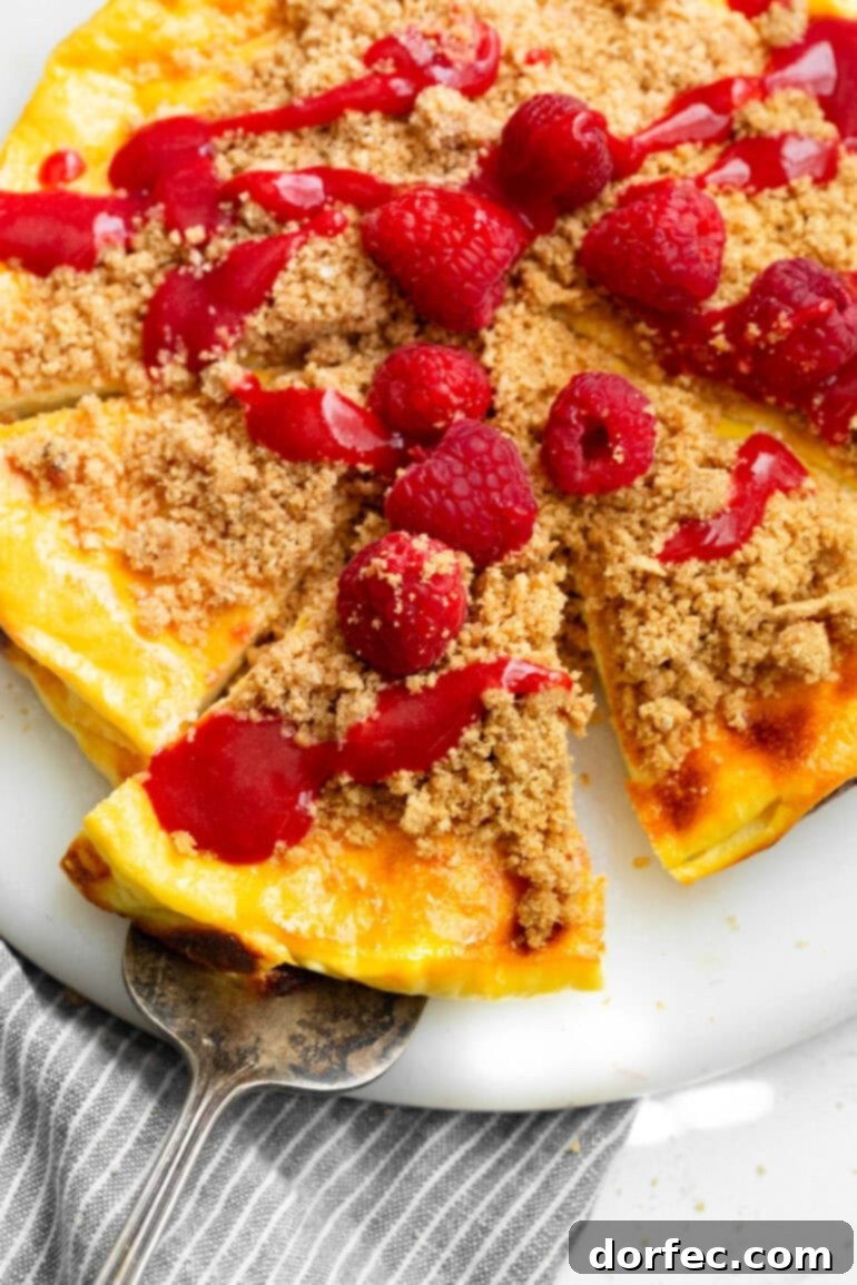 Creamy Baked Yogurt Cheesecake 2 A photo of a slice of cheesecake baked yogurt on a serving tray, topped with fresh strawberries and graham cracker crumble.