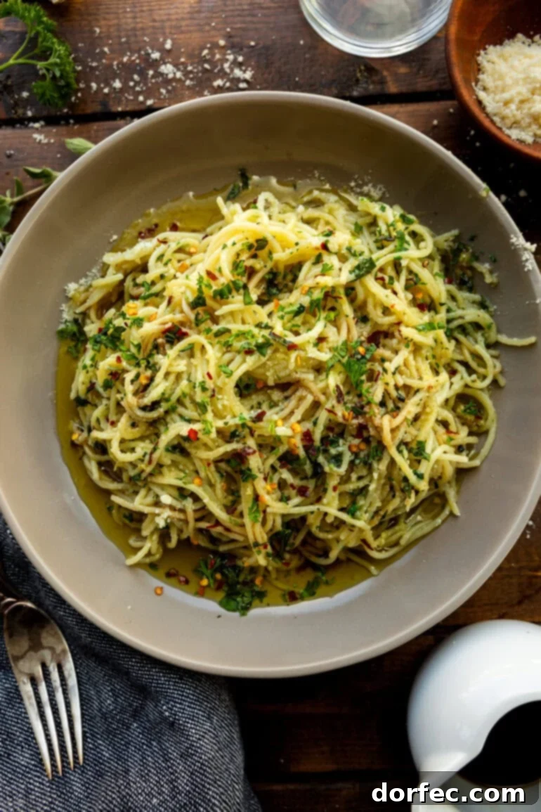 A vibrant bowl of spaghetti aglio e olio, showcasing the glossy pasta strands, fresh olive oil, and a light sprinkling of Parmesan cheese and herbs.