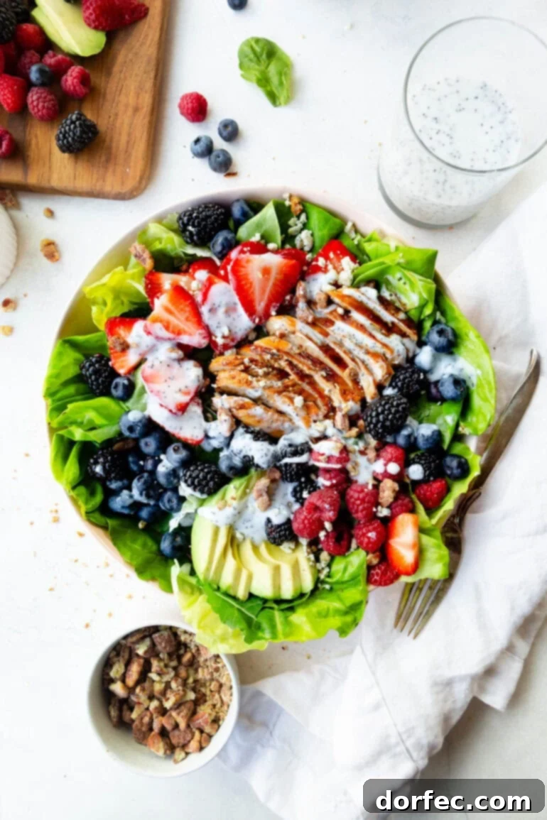 An overhead shot of a large bowl of Berry Avocado Chicken Salad, showcasing perfectly sliced chicken breast, vibrant fresh berries, creamy avocado slices, and a rich, creamy poppyseed dressing.