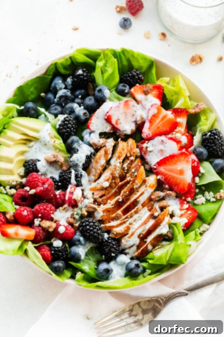 An inviting overhead shot of a large bowl of Berry Avocado Chicken Salad, featuring tender grilled chicken, creamy avocado, and a burst of vibrant berries, all coated in a luscious, creamy poppyseed dressing.