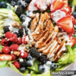 A vibrant Berry Avocado Chicken Salad, garnished with perfectly grilled chicken and a creamy dressing.