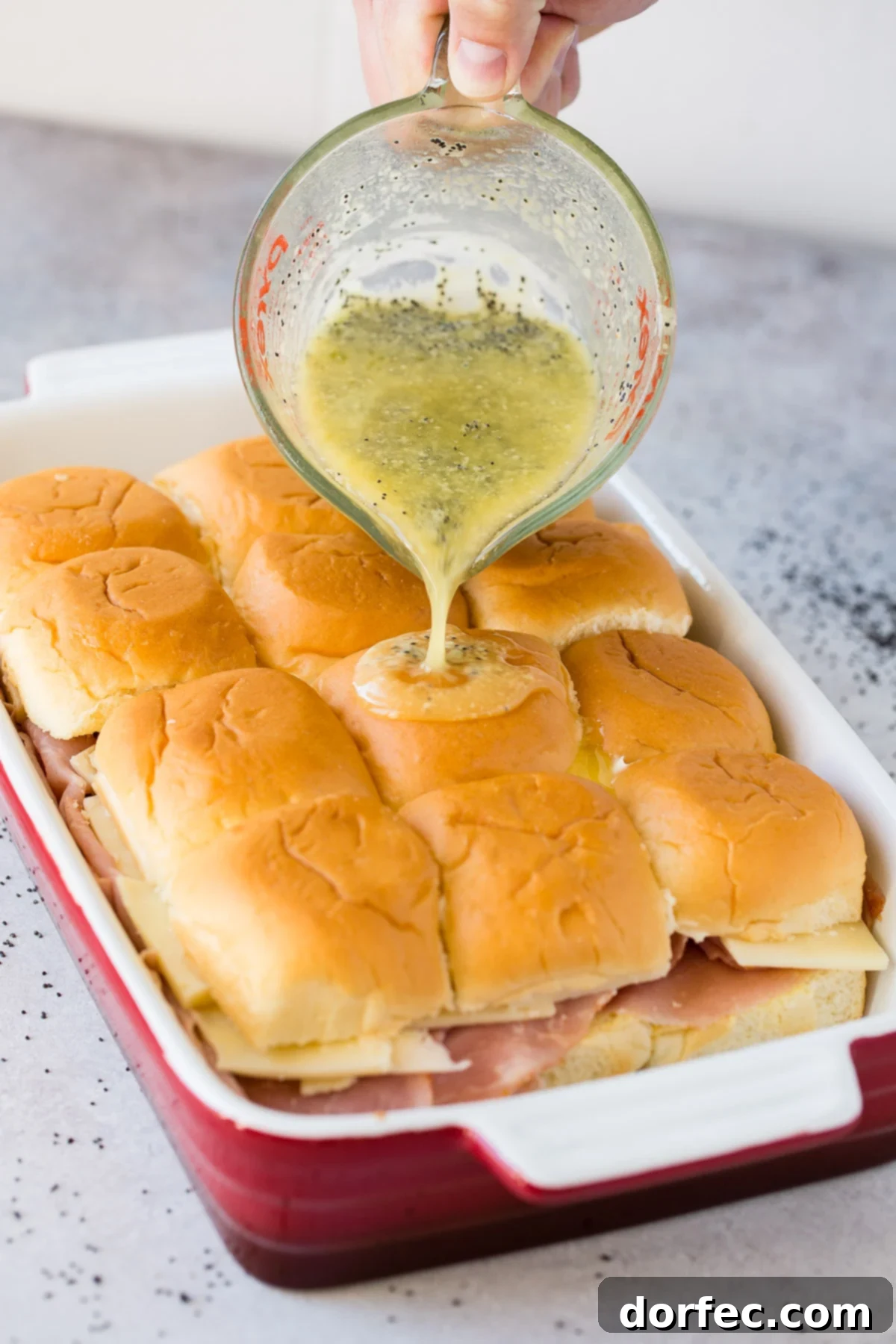 Classic ham and cheese sliders on soft Hawaiian rolls, generously topped with a simple yet flavorful poppy seed dressing.