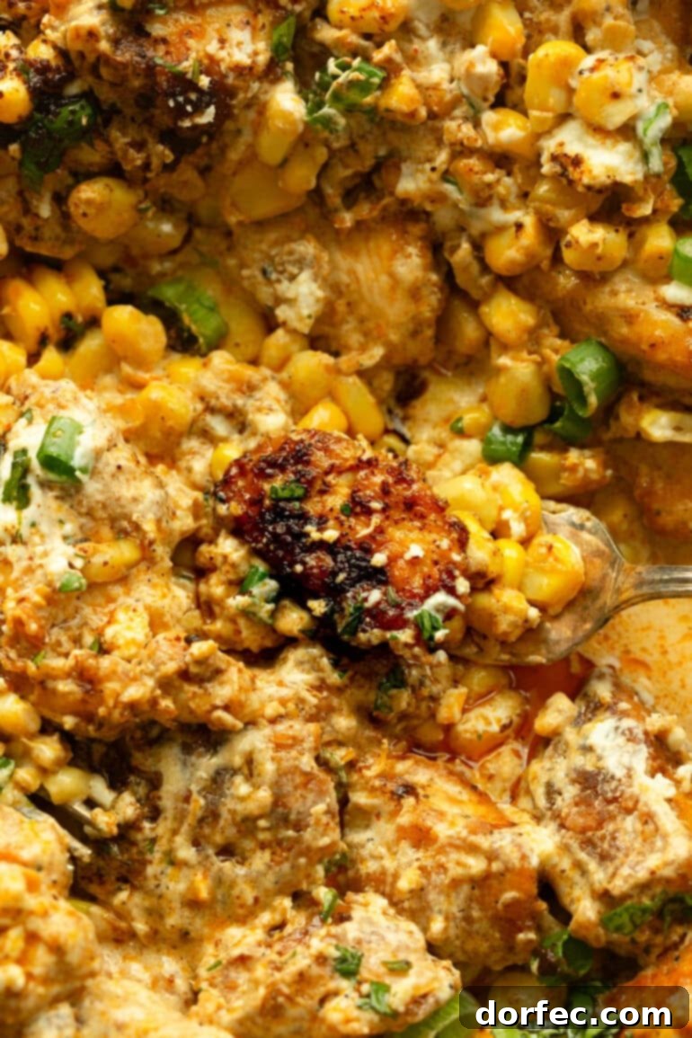 Creamy Mexican Street Corn Chicken Skillet 10 A golden brown piece of chicken being scooped from a dish of creamy Mexican street corn chicken, highlighting the tender chicken.