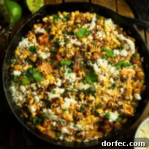 Creamy Mexican Street Corn Chicken Skillet 12 A photo of a cast iron skillet of cooked chicken chunks mixed with Mexican street corn, perfect for a family dinner.