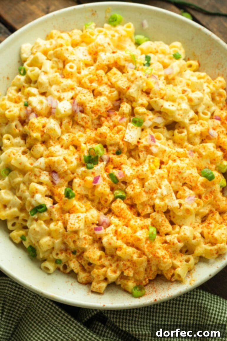 A close-up shot of a creamy deviled egg pasta salad, richly textured and garnished with diced green onions and red onions, inviting a delicious bite.