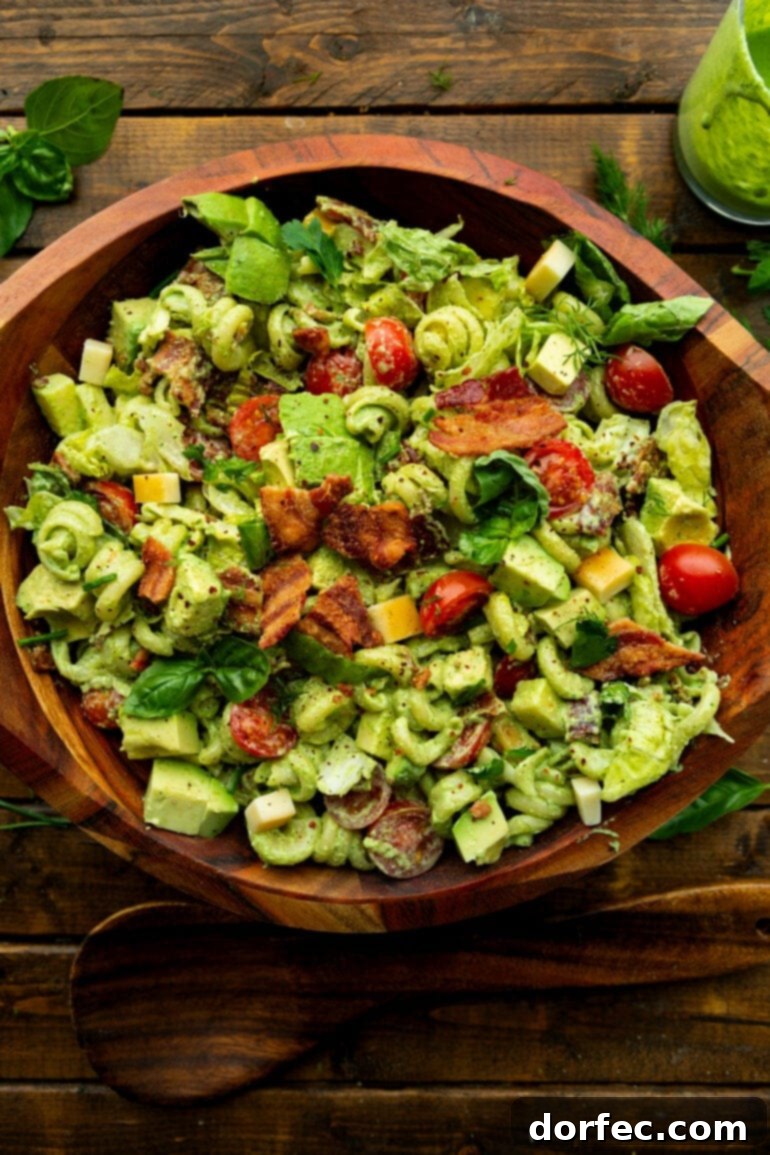 a photo of a large wooden serving bowl full of creamy blt pasta salad