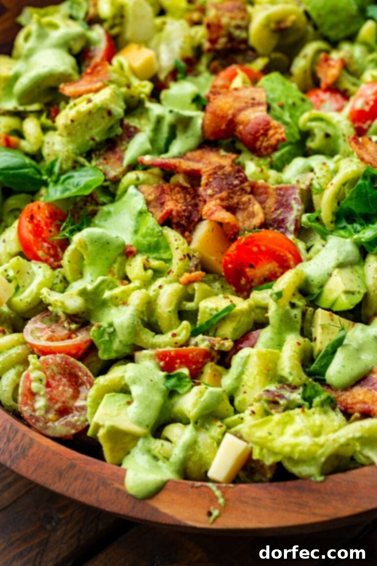 a close up photo of a creamy blt pasta salad with crispy bacon pieces, halved cherry tomatoes, chopped romaine lettuce and pasta
