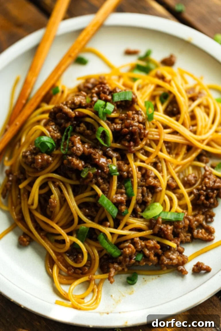 A vibrant photo of saucy Korean ground beef tossed with perfectly cooked spaghetti noodles, generously garnished with freshly sliced green onions, ready to be enjoyed.