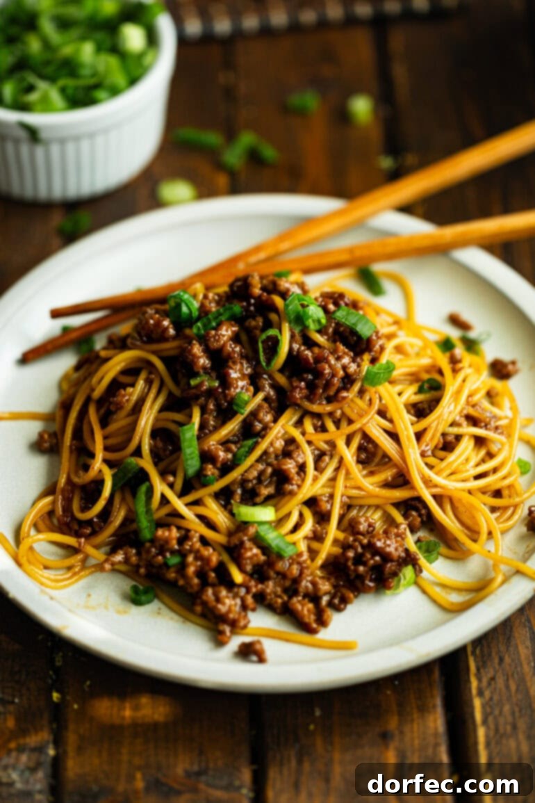 A beautifully plated dinner of spaghetti noodles tossed with saucy Korean ground beef and vibrant sliced green onions, ready to be enjoyed.
