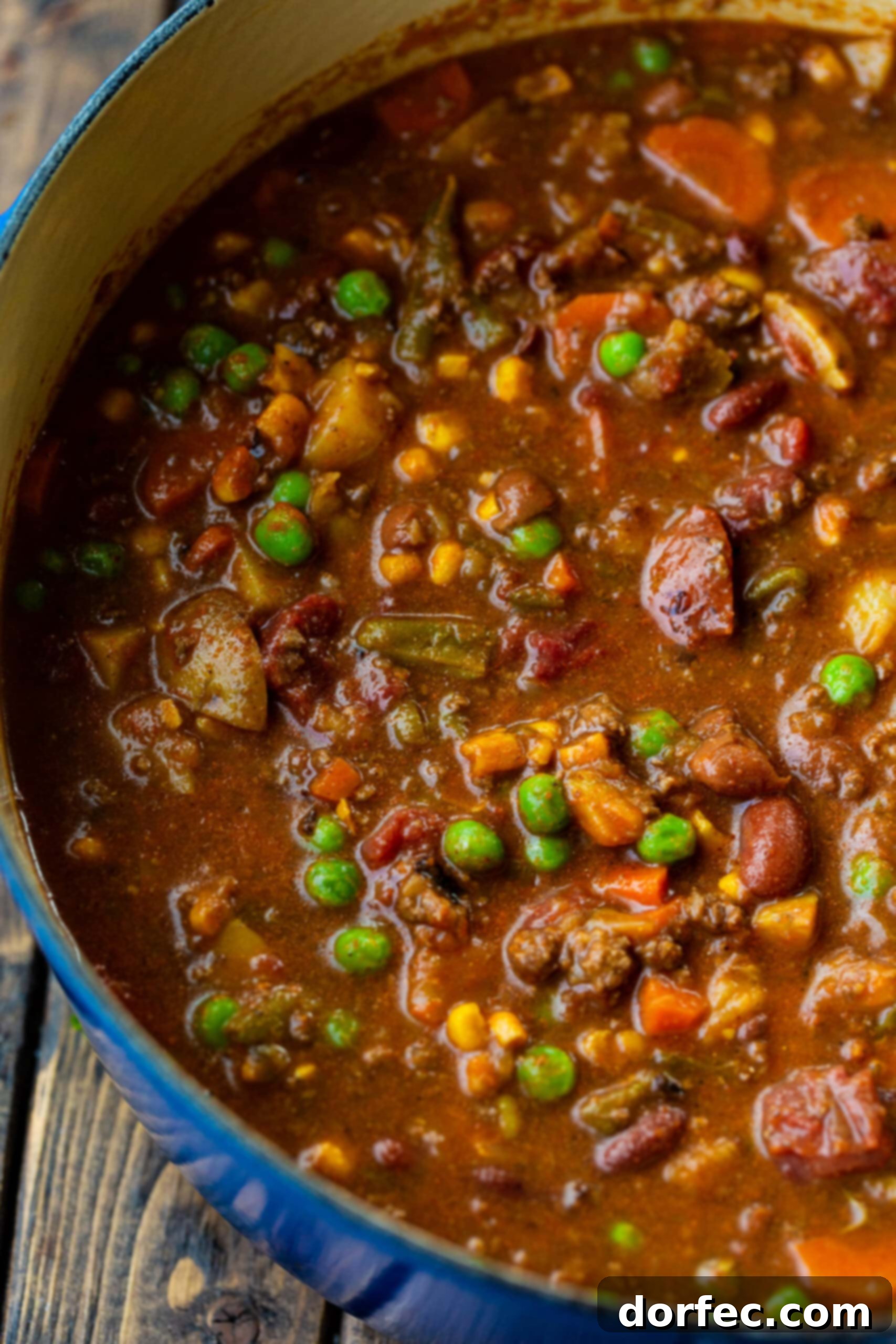 Hearty Taco Stew in a Dutch Oven A close-up shot of a steaming Dutch oven filled with a rich, chunky taco stew, showcasing tender pieces of ground beef, colorful peas, carrots, and potatoes simmering together.