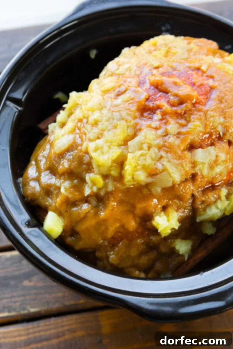Perfectly Tender Slow Cooker Ham 5 A tempting photo of a whole glazed ham, perfectly nestled in a slow cooker, adorned with a vibrant pineapple glaze, ready for a delicious meal.