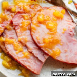 Perfectly Tender Slow Cooker Ham 10 A photo of a spiral cut ham sitting on a serving platter topped with a juicy pineapple glaze