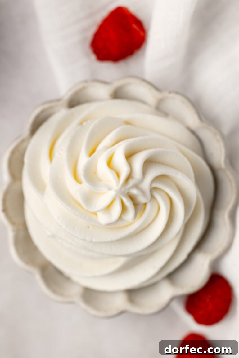 Fluffy Tangy Cream Cheese Frosting 12 A stunning top-down view of a small glass bowl filled with perfectly piped whipped cream cream cheese frosting, highlighting its beautiful texture and readiness for serving.