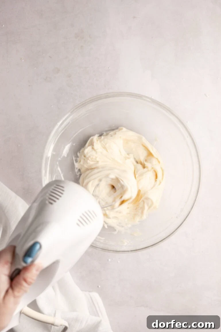 Fluffy Tangy Cream Cheese Frosting 6 Step 3: The cream cheese mixture being beaten to a smooth and creamy consistency, ensuring no lumps remain before the next step.