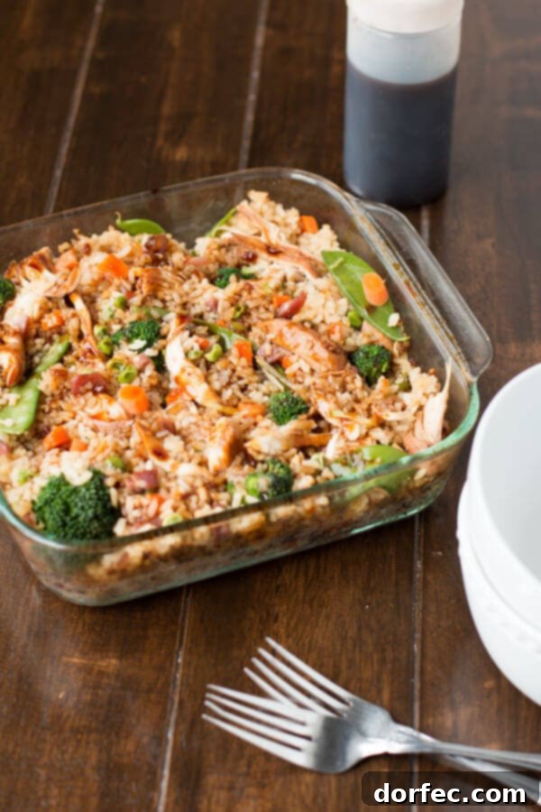 Hearty Teriyaki Chicken Casserole: A comforting and satisfying one-pan meal. A square glass casserole dish filled with the vibrant Teriyaki Chicken Casserole, showcasing the fluffy fried rice, large, tender pieces of teriyaki chicken, and a medley of colorful stir-fried vegetables, ready to be served.