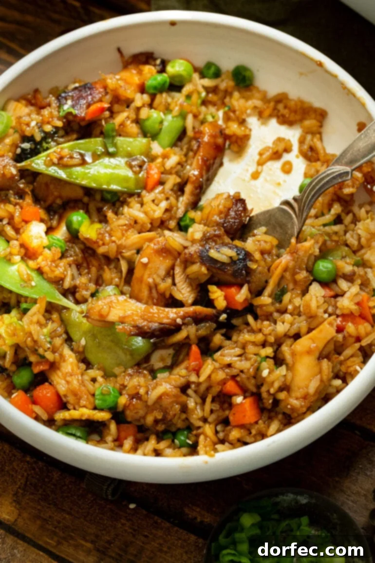 Teriyaki Chicken Casserole: A perfect make-ahead meal for family dinners. A large bowl filled with Teriyaki Chicken Casserole, showcasing the perfectly mixed fried rice, tender chicken, and various vegetables, with a fork poised to scoop up a delicious bite.