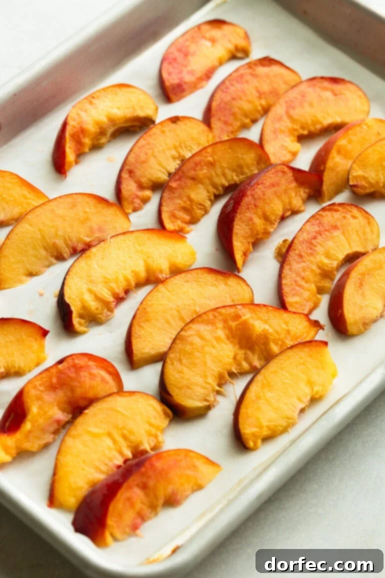 Close-up of evenly spaced peach slices on a baking sheet, prepped for flash-freezing.
