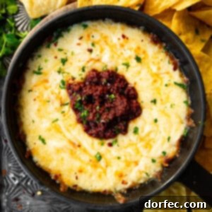 A bubbling skillet of Chorizo Queso Fundido, garnished with fresh cilantro and served with tortilla chips.