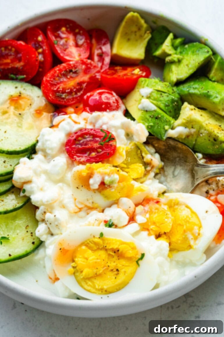 The Trending Protein Power Bowl: Eggs and Cottage Cheese 6 A close-up shot of a savory cottage cheese breakfast bowl, overflowing with wholesome goodness, featuring perfectly cooked hard-boiled eggs, vibrant avocado chunks, sweet grape tomatoes, and crisp cucumber slices, demonstrating a fresh and appealing meal option.