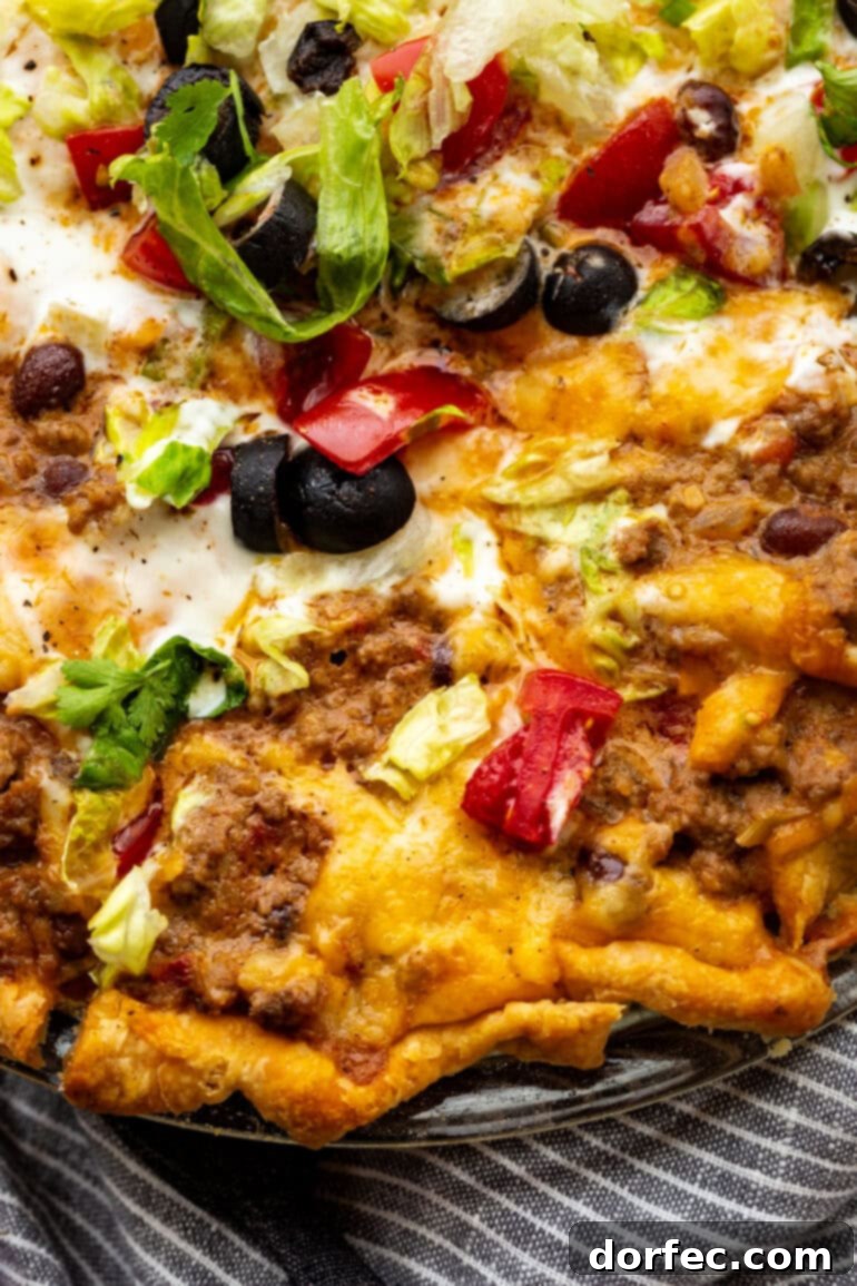 A perfectly portioned slice of gooey, cheesy Taco Pie being gently lifted from a full pie plate, revealing its delicious layers and inviting texture. A comforting and easy dinner idea.