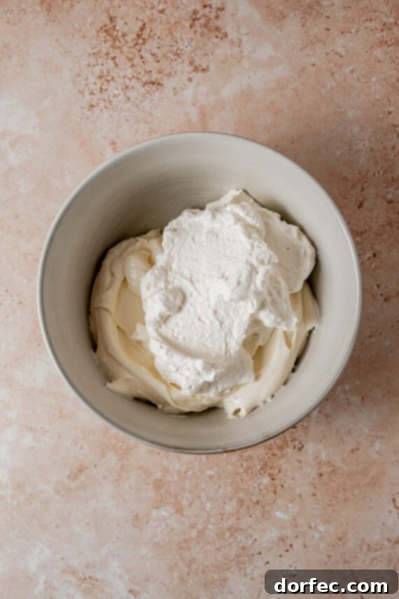Folding whipped cream into the cheesecake mixture.
