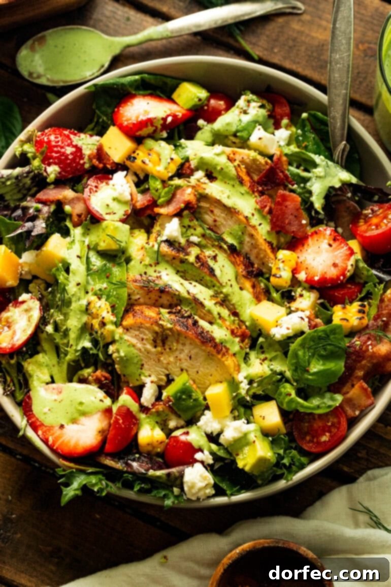 A vibrant, large serving bowl filled with mixed greens, succulent sliced grilled chicken breast, sweet charred corn kernels, juicy halved cherry tomatoes, and a generous drizzle of creamy basil dressing.