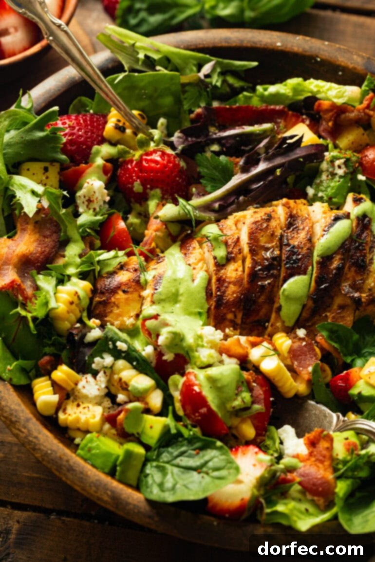 An enticing close-up photo of a generous summer grilled chicken salad, artfully arranged with mixed greens, sliced chicken breast, corn, tomatoes, and topped with a luscious drizzle of creamy basil dressing, ready to be enjoyed.