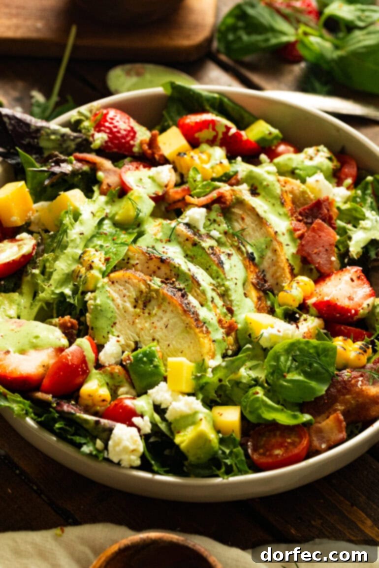 A beautifully presented grilled sliced chicken breast atop a colorful summer salad, generously drizzled with homemade basil dressing, showcasing the vibrant ingredients and appealing textures.