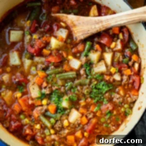 Simple & Satisfying Ground Beef Vegetable Soup 9 A large pot of ground beef vegetable soup topped with minced fresh parsley with a wooden spoon in the bowl