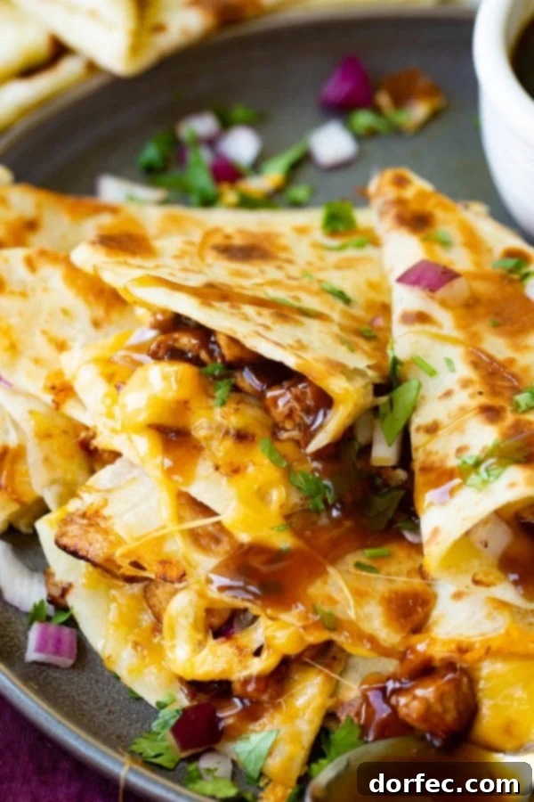 Teriyaki Chicken Quesadilla A photo of a slice of teriyaki chicken quesadilla garnished with minced red onion and chopped fresh cilantro.