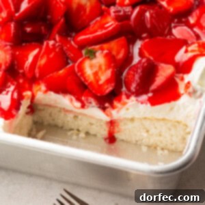 A photo of a single layer white cake topped with cream cheese frosting and juicy red strawberries with some slices removed so you can see the cross section