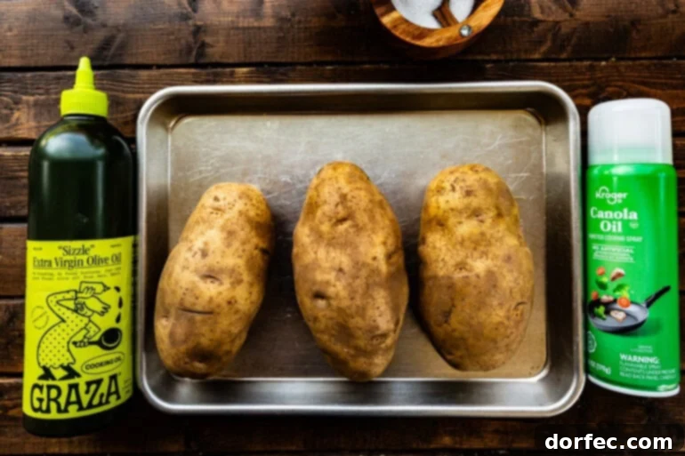 Perfectly Crispy Air Fryer Baked Potatoes 3 A few potato on a pan with oil on either side. Dinner just got easier! Learn how to make restaurant-style baked potatoes in the air fryer—crisp, fluffy, and customizable. #AirFryerPotatoes #ComfortFood #PotatoRecipes