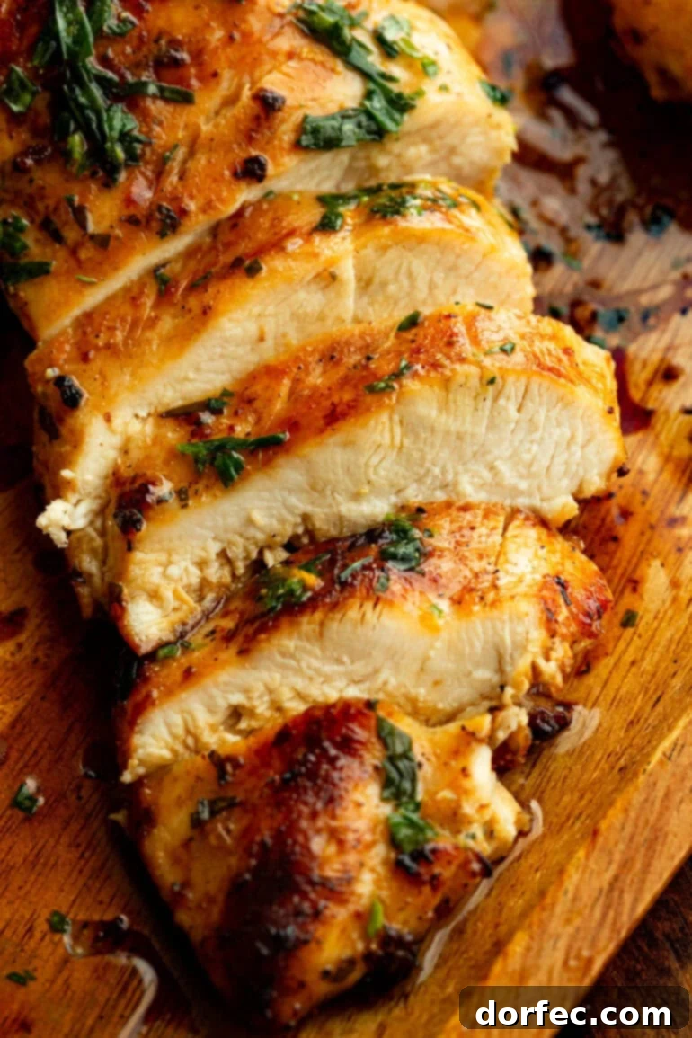 Close-up of a perfectly sliced citrus-marinated grilled chicken breast, revealing its juicy, tender interior, distinct charred grill marks, and a sprinkle of fresh herbs on top.