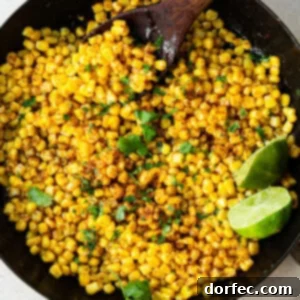 a cast iron skillet with charred corn, chopped cilantro, and lime wedges