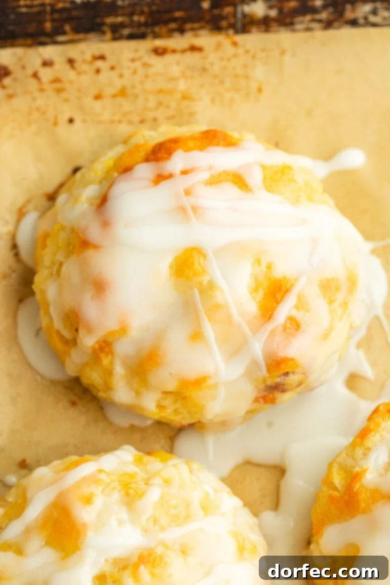 Golden brown biscuit with visible chunks of juicy peach and a smooth glaze dripping down the sides.