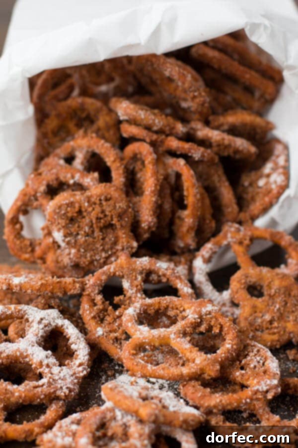 The Best Churro Pretzels Recipe to Make Hand reaching into a bowl of perfectly coated Churro Pretzels, tempting and ready to eat
